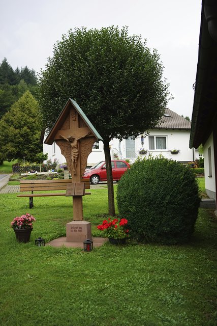 Das alpenländisch anmutende Holzkreuz mit einer Darstellung von Jesus am Kreuz erinnert an die einstigen Hochwasser-Katastrophen im Erf- und Kaltenbachtal.