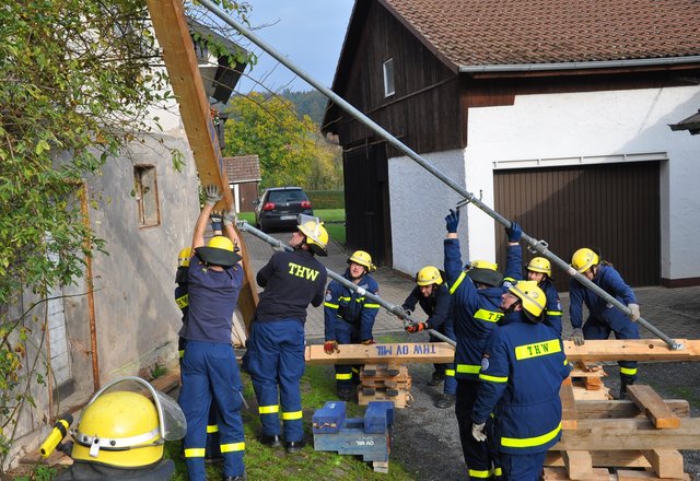Mit vereinten Kräften wird ein ASH-Element am Einsatzort aufgerichtet. Ein Helfer beobachtet ständig das marode Haus, um evtl. Veränderungen umgehend mitzuteilen.