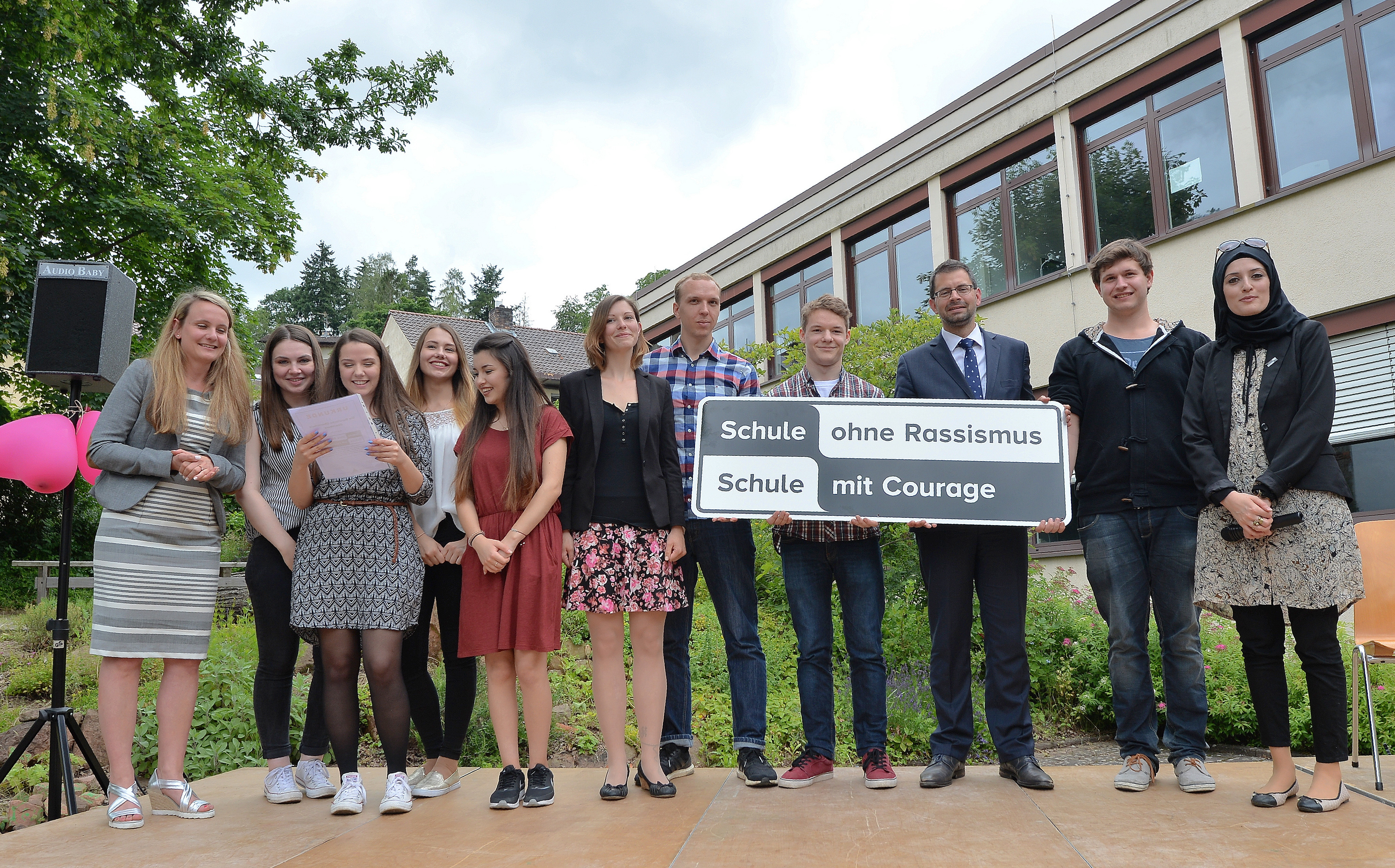 Das Schild mit der Aufschrift „Schule ohne Rassismus – Schule mit Courage“ wird künftig alle Mitglieder der Schulfamilie der Fachoberschule Obernburg daran erinnern, gegen Rassismus einzutreten. Das Bild zeigt das Schülerteam der FOS mit (links) Projektbetreuerin Kawan sowie (rechts) Zehranur Aksu und Landrat Jens Marco Scherf (dritter von rechts).