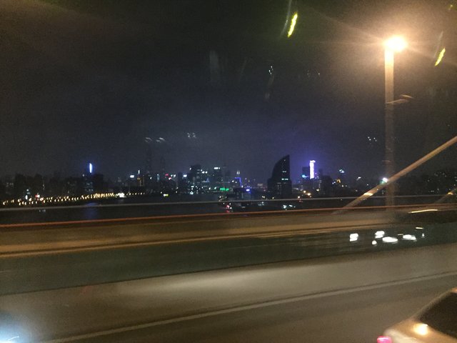 Die Hafenbrücke bei Nacht, hinten eines der beleuchteten Hochhäuser am Fluss