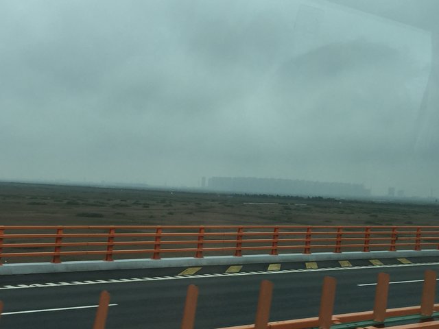 Die Autobahn von Shanghai nach Ningbo nimmt eine "Abkürzung" über die Hangzhou-Bay auf der aktuell längsten Brücke der Welt ... hinten erkennt man eine Trabantenstadt mit unzähligen Hochhäusern