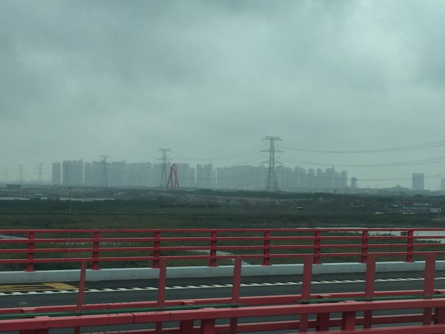 Die Autobahn von Shanghai nach Ningbo nimmt eine "Abkürzung" über die Hangzhou-Bay auf der aktuell längsten Brücke der Welt ... hinten erkennt man eine Trabantenstadt mit unzähligen Hochhäusern