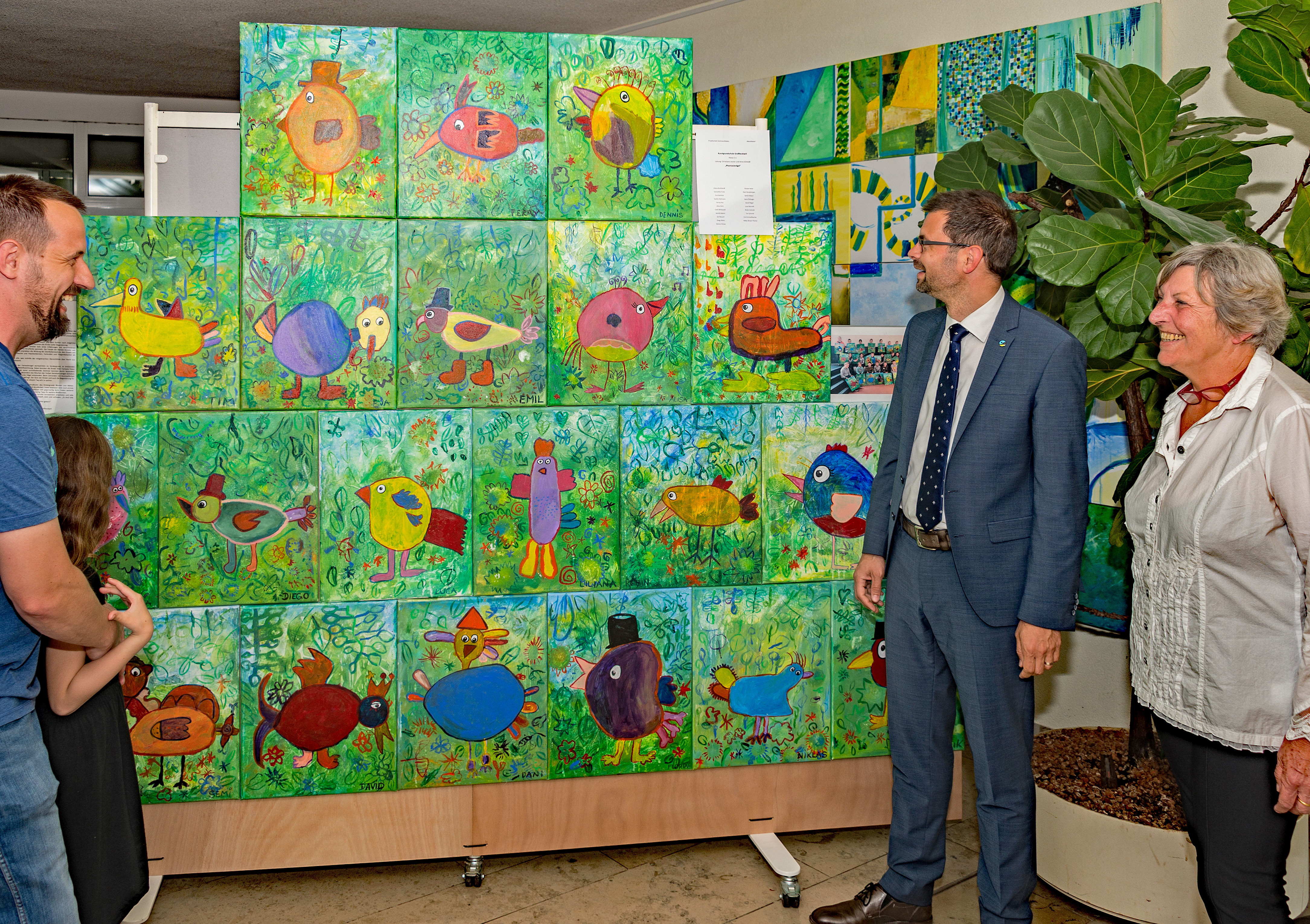 Landrat Jens Marco Scherf und Barbara Klietsch (rechts) nahmen beim Rundgang durch die Ausstellung unter anderem dieses Werk („Phantasievögel“ der Kunstgrundschule Großheubach) in Augenschein, begleitet von einer jungen Künstlerin mit ihrem Vater.