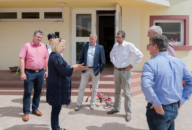 Neubau oder Umbau für eine zweite Krippengruppe? Mit dieser Frage beschäftigten sich Landrat Jens Marco Scherf, Bürgermeister Dietmar Wolz (mitte, von links) und die weiteren Mitglieder der Delegation – hier mit der Leiterin des Kindergartens, Ulrike Karch (vorne).