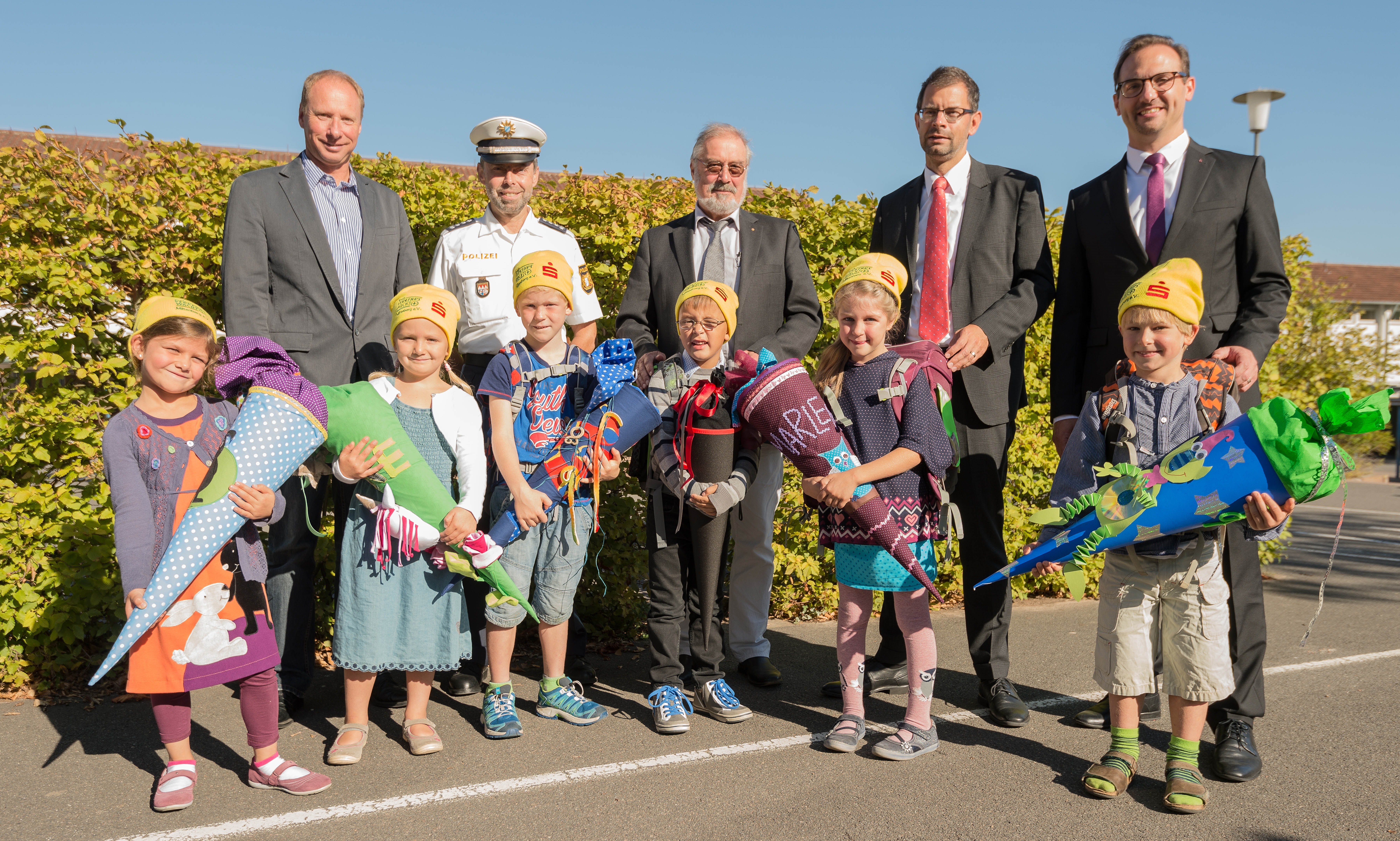 Mit den neongelben Schulmützen, die alle eingeschulten Kinder bekamen, sind sie gut im Straßenverkehr zu erkennen. Darüber freuen sich (hinten von links) Malte Loevenich (Kreisverkehrswacht), Bernhard Wenzel (Polizei), Klaus Huhn (Stadt Miltenberg), Landrat Jens Marco Scherf und Matthias Dick (Sparkasse)