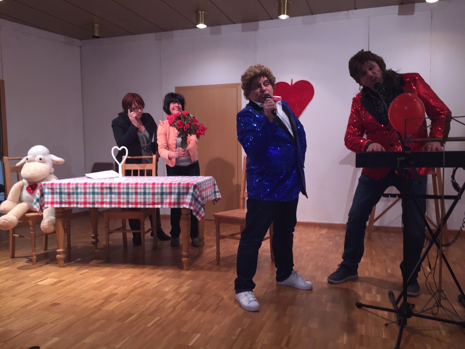 Frank (Gebhard Motzel) und Bodo (Werner Becker) bei einer "Gesangsprobe". Regina Rautenstengel (Renate Miltenberger) und die Fanclub-Leiterin Mira Bell (Anita Keller) beobachten die Beiden mit unterschiedlichen Absichten. Das Schaf spielt keine große Rolle.