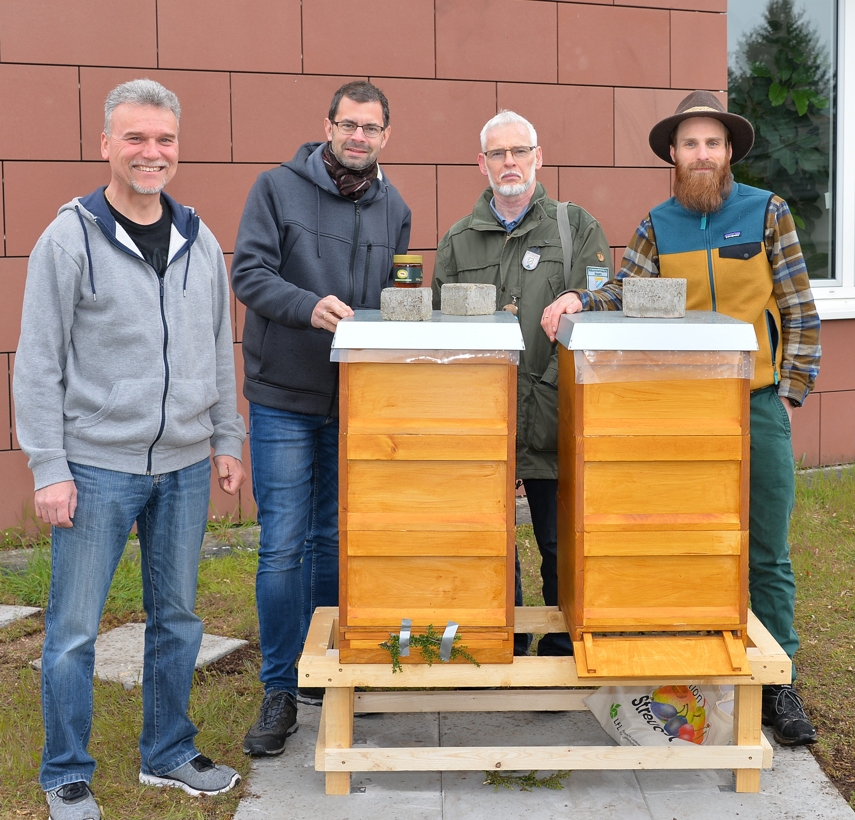 Zwei Bienenkästen mit bis zu 80.000 Bienen stehen seit dem Wochenende auf dem Gelände des Landratsamts Miltenberg. Darüber freuen sich (von links) der Imker-Kreisvorsitzende Matthias Meidel, Landrat Jens Marco Scherf sowie Wolfgang und Daniel Neuberger.