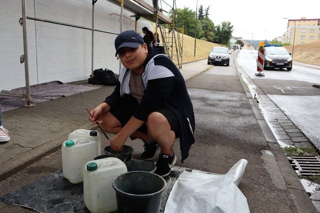Schüler/innen der Mittelschule Erlenbach arbeiten das Wandbild farblich aus. 