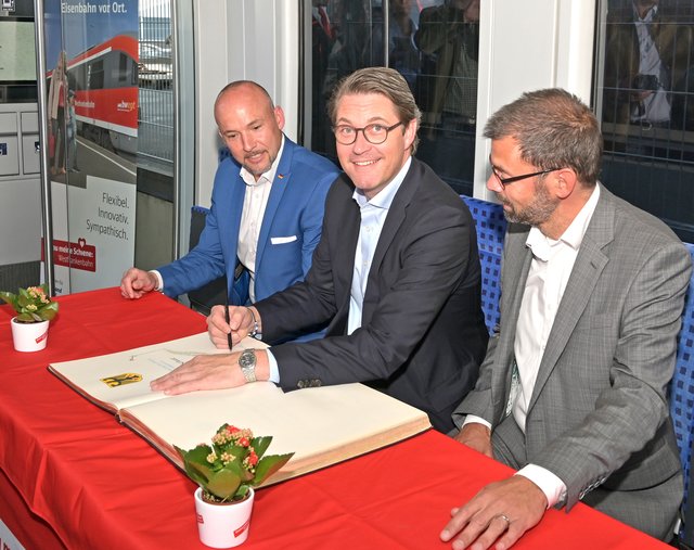 Der Bundesverkehrsminister, der auf Einladung von Alexander Hoffmann (links) und Landrat Jens Marco Scherf (rechts) im Landkreis Miltenberg zu Besuch war, trug sich auch in das Goldene Buch des Landkreises ein.