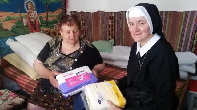 Eine Franziskanerschwester übergibt Sachspenden an eine Bewohnerin eines Altenheims in Rumänien. | Foto: Verein Nächstenliebe
