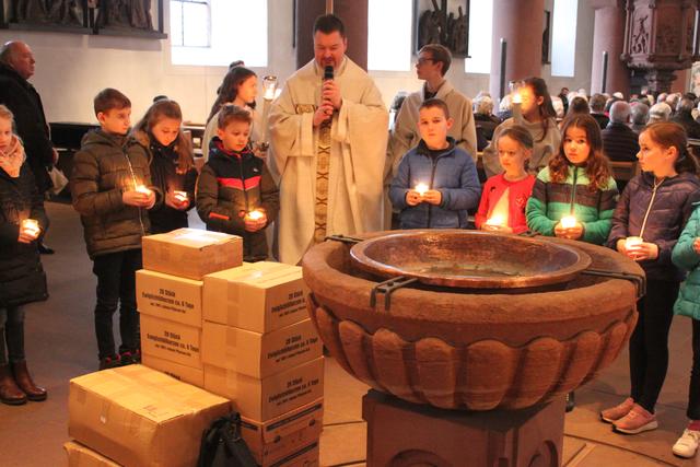 Pfarrer Jan Kölbel mit den Kommunionkindern bei der Kerzensegnung am Taufstein