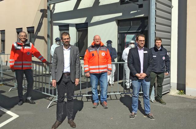 Bei der Eröffnung des Testzentrums an der Helios Klinik Miltenberg am 30. März.2020 überzeugen sich (von links) der Geschäftsführer des BRK-Kreisverbands Edwin Pfeifer, Landrat Jens Marco Scherf, BRK-Kreisbereitschaftsleiter Thomas Kling, der Geschäftsführer der Helios Kliniken Miltenberg-Erlenbach Sven Axt und der Leiter Rettungsdienst im BRK-Kreisverband Björn Bartels vom reibungslosen Ablauf bei der Testung. Im Hintergrund Dr. Marion Schwarzkopf von der Kassenärztlichen Vereinigung Bayerns, assistiert von medizinischem Fachpersonal vom BRK-Kreisverband in Schutzanzügen.