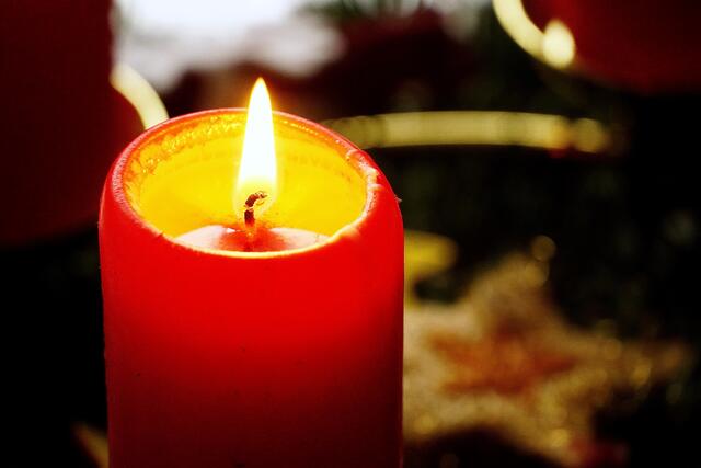 Auf Weihnachten zu: ein erstes Kerzenlicht leuchtet am häuslichen Adventskranz im dunklen Zimmer, spendet Wärme, verheißt symbolhaft Hoffnung in schwieriger Pandemie-Zeit während draußen Kälte und Schnee den Winter einläuten. Foto Roland Schönmüller