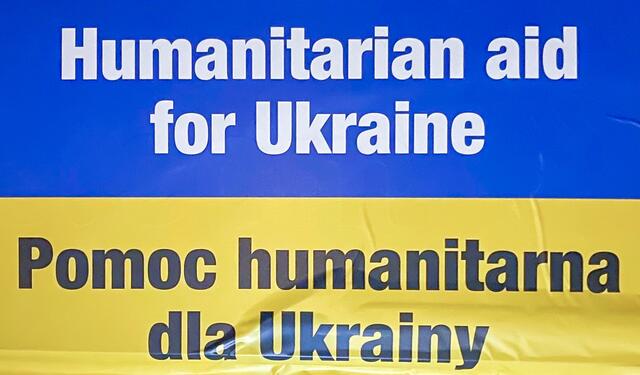 Deutlich sichtbar an den Lastwagen angebracht: Banner in den ukrainischen Landesfarben mit der Aufschrift „Humanitarian aid for Ukraine“.