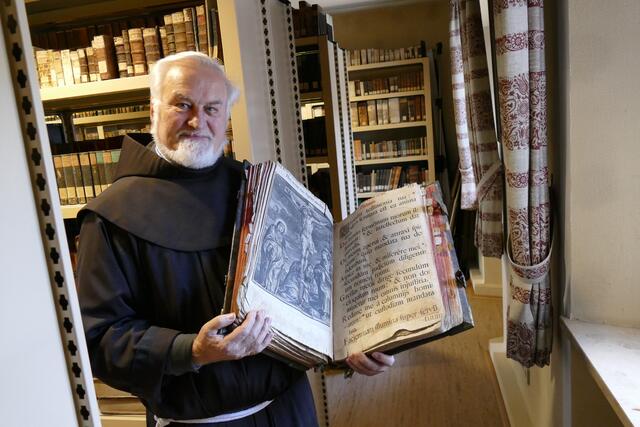 Pater Richard Hessdörfer beim Präsentieren historischer Bücher