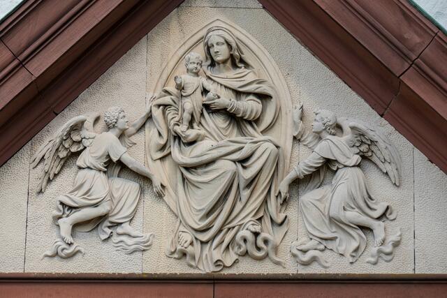 Das Marmorrelief des Tympanons zeigt die Gottesmutter mit dem Jesuskind auf dem Arm, mit zwei schwebenden Engeln