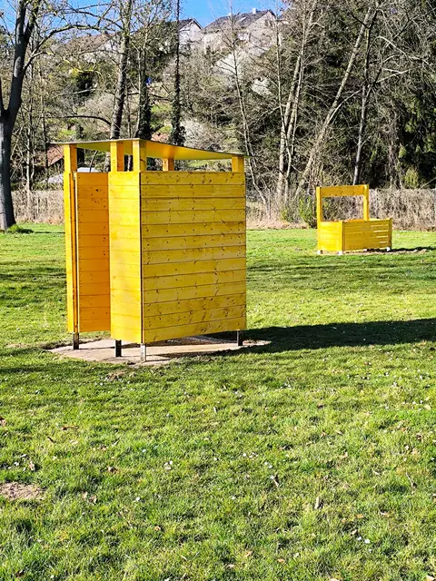 Normale Umkleide mit Dach und Bänkle. Im Hintergrund eine Mülltonnenumrandung. 