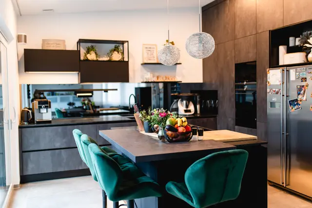 Spachtelbeton, schwarzer Mattlack und Spiegelrückwand von WM Küchen + Ideen