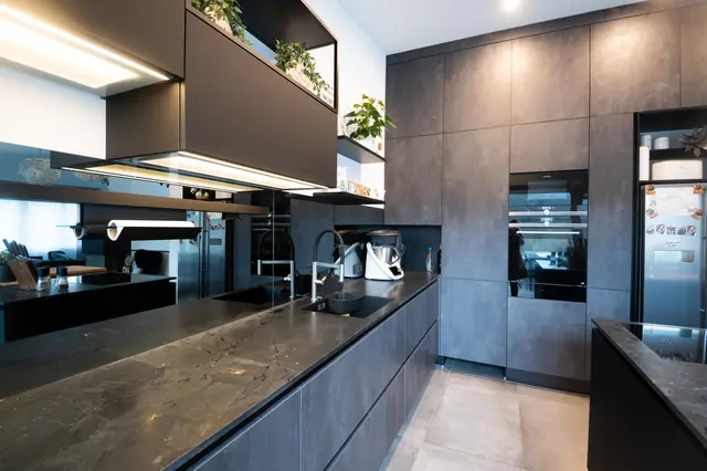 Spachtelbeton, schwarzer Mattlack und Spiegelrückwand von WM Küchen + Ideen