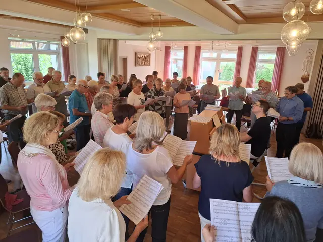 Foto: Über sechzig Sängerinnen und Sänger scharen sich um den TOP-Dirigenten Ernie Rhein beim Einstudieren von "So soll es sein"