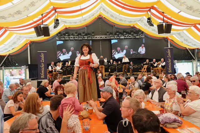 Jetzt wird‘s sportlich!“ schmunzelte zum Konzertende hin die junggebliebene Sängerin Rita Barth, sie hatte ihre weißen Sportschuhe angezogen, kletterte auf einen Messezelt-Tisch und lud das ohnehin schon begeisterte Publikum erfolgreich zum Mitsingen, Schunkeln und Tanzen ein. 