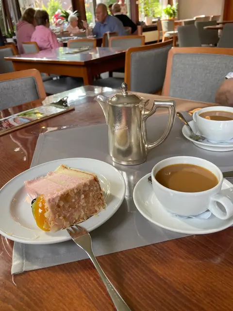 Ich bestelle ein Kännchen Kaffee – kein Becher, kein Pappding,
sondern ein echtes Retro-Kaffeekännchen annodazumal,
In Silber, leicht angeschlagen, aber voller Würde.
Es dampft wie ein Theaterstück,
und ich nippe wie ein Philosoph auf Kurzurlaub.

Dazu ein Stück Torte, das sich nicht entscheiden kann,
ob es Dessert oder Denkmal sein will.
Der Mürbeteig spricht Bände,
die Sahne flirtet mit dem Löffel,
und die Kirsche oben drauf schaut mich an,
als wüsste sie mehr über mein Leben als ich selbst.