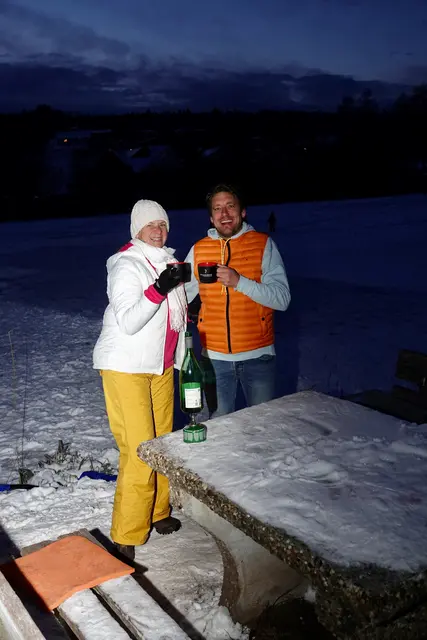 Viele bleiben länger als geplant, weil dieser Kloster-Eisweiher etwas besitzt, das man nicht oft erlebt: Wintermut und Wintermagie zugleich. Ein erwachsenes Paar trinkt Punsch am Ufer, gutgelaunte Mütter sind mit ihren fröhlichen Kindern auf sicherem Eisdecken-Terrain unterwegs.