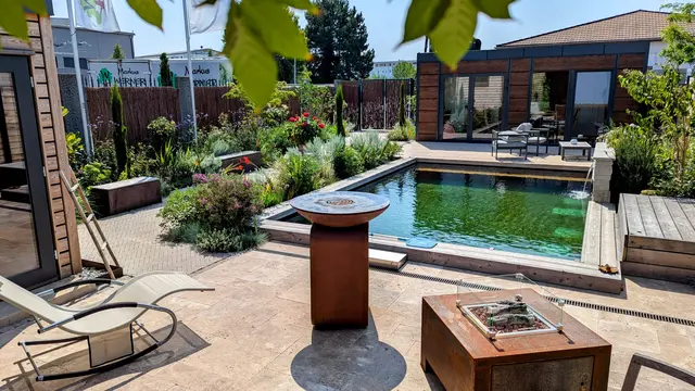 Schaugarten mit Schwimmteich, verschiedenen Bodenbelägen, Außensauna, Feuertisch, Wasserwand, Ruhe- und Essbereich. | Foto: Schaugarten Werner Gartengestaltung, Elsenfeld