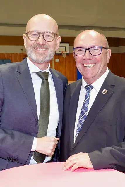 Während die Rekruten noch Glückwünsche entgegennahmen, verlagerte sich das Geschehen für Interessenten langsam in die Sporthalle, wo Dr. Peter Tauber (hier links mit Klingenbergs Bürgermeister Ralf Reichwein) bereits wartete.

Der ehemalige Staatssekretär und CDU‑Generalsekretär sprach dort über die Bundeswehr, über ihre Akzeptanz, über Zahlen, die erstaunlich hoch sind in einem Land, das sich lange schwer tat mit Uniformen im öffentlichen Raum. 

Mehr als vier Fünftel der Bevölkerung halten die Bundeswehr für notwendig, mehr als die Hälfte könnte sich vorstellen, selbst Dienst an der Waffe zu leisten. Tauber sprach von einem neuen Bewusstsein, das nötig sei, von Krisen, die näher rücken, und von Kommunen, die Sicherheit nicht länger als abstrakte Bundesaufgabe betrachten können. Die Sporthalle, sonst ein Ort für Volleyball und Schulsport, wurde für mehr als zwei Stunden zu einem politischen Resonanzraum. 