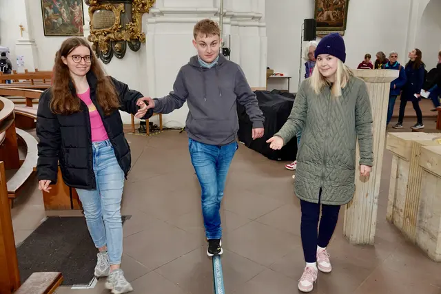 Und so bleibt alles ein Balanceakt, wie bei Ministrant Marco aus Eltmann in der Kirche von Stift Hauck, der von zwei jungen Frauen Marie Christin Herzog (rechts) und Helena Wissel (links) von der Ehe- und Familienseelsorge aus Aschaffenburg erfolgreich über eine Slackline geleitet wird. 