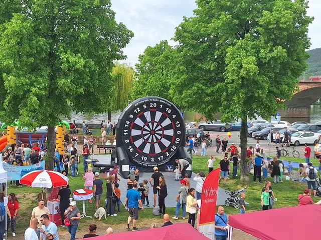 Das Bild zeigt viele Menschen verschiedener Alterstufen beim Besuch des Inklusionstags am Mainufer. Man sieht die Beschäftigungsangebote Fußball-Dart und Hüpfburg. Außerdem sind auf dem Bild ein Infostand der AWO und ein Fahnenaufsteller des inklusiven AWO-Cafés A(r)trio.