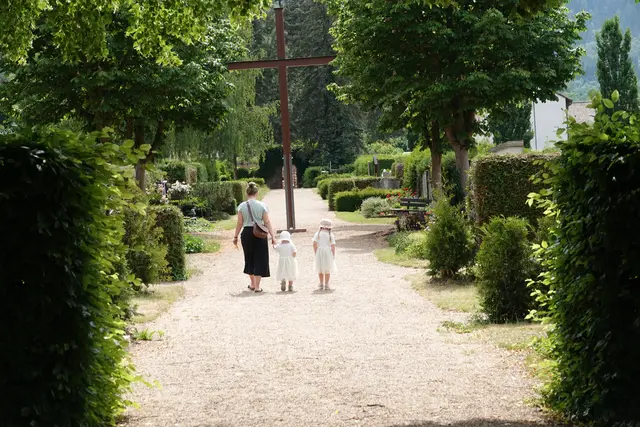 Die Besucher bewegen sich langsamer als sonst. Vielleicht, weil die Natur in dieser Übergangsphase eine eigene Sprache spricht. Die Hecken stehen dicht, aber noch nicht schwer. Der Lavendel beginnt zu duften, aber noch nicht zu dominieren. Die Amseln singen, als wollten sie den Mai verabschieden und den Juni zugleich begrüßen. Es ist ein Moment, in dem der Friedhof wie ein Kalenderblatt wirkt, das sich gerade umblättert.