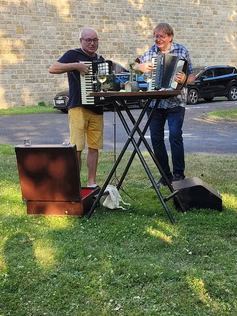 Begegnung am Glockenturm an der St.-Pius-Kirche - Alfred Happel und Pfarrer Dr. Heinrich Skolucki überraschen die Besucher mit ihrem Spiel auf dem Akkordeon