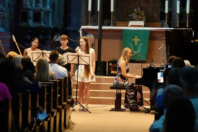 BU 2: Mit anspruchsvollen Pop-Arrangements, jazzigen Rhythmen und mitreißenden Musical-Melodien entfalteten die Ensembles ihre immense stilistische Bandbreite. Hier v. l. Liam O’Neill, Nika Karian und Daria Kokoariev beim Gesang von John Denvers „Leaving on a Jet Plane“ mit Lehrerin Sonja Freitag am Klavier. Foto Roland Schönmüller 