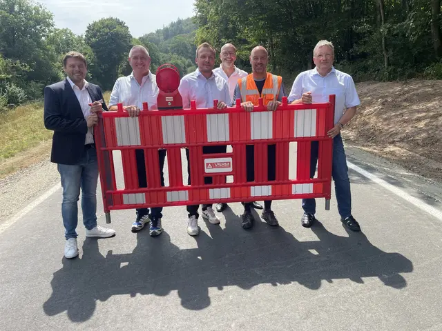 Kaltenbachtal, Kreisstraße, klare Kante: Grünes Licht für die MIL 14
Eichenbühl-Pfohlbach / Walldürn-Kaltenbrunn. Das Kaltenbachtal hat wieder Takt aufgenommen: Seit Freitagnachmittag, 31. Juli 2026, rollt der Verkehr auf der Kreisstraße MIL 14 zwischen der Einmündung der MIL 20 an der Lauersmühle und der MIL 13 bei Pfohlbach wieder frei. Landrat Björn Bartels gab die Strecke um 14 Uhr offiziell frei — ein kurzer Akt am Straßenrand, der nach Monaten der Sperrung für viele Verkehrsteilnehmerinnen und Verkehrsteilnehmer mehr bedeutete als nur die Öffnung eines Asphaltbandes.
Seit dem 13. März war der rund 1,5 Kilometer lange Abschnitt umfassend erneuert worden. Die Fahrbahn wurde verbreitert, mit neuen Asphaltschichten versehen und in schwierigen Böschungsbereichen gesichert. Wo zuvor Enge und Ausweichmanöver den Begegnungsverkehr prägten, sollen nun bessere Sicht, mehr Breite und neue Schutzplanken für ein spürbares Plus an Verkehrssicherheit sorgen.
Die Maßnahme war technisch nüchtern, in der Wirkung aber durchaus weitreichend: Erdarbeiten zur Verbreiterung der Fahrbahn, die Herstellung eines standfesten Banketts, Anpassungen an Wirtschaftswegen, neue Markierungen sowie die Erneuerung und Anpassung der Entwässerung gehörten zu den Hauptleistungen. Ausgeführt wurden die Arbeiten von der Firma Leonhard Weiss GmbH &amp; Co. KG aus Göppingen. Die Kosten für den zweiten Bauabschnitt belaufen sich auf rund 1,35 Millionen Euro; beide Bauabschnitte zusammen liegen bei insgesamt etwa 2,4 Millionen Euro.
Besonders im ländlichen Raum zeigt sich der Wert solcher Investitionen nicht allein in Zentimetern Fahrbahnbreite. Für Pendlerinnen und Pendler, für Busse, landwirtschaftliche Fahrzeuge, den Schwerverkehr und nicht zuletzt für Rettungsdienste zählt jede sichere Verbindung. Landrat Björn Bartels sprach daher von einer verbesserten Infrastruktur im ländlichen Raum, von einer optimierten Versorgung im Rettungswesen und von einer besseren Anbindung zwischen Bayern und Baden-Württemberg.
Dass Straßenbau im Kaltenbachtal nicht nur eine Sache von Maschinen, Asphalt und Markierung ist, zeigte der Blick auf Natur- und Artenschutz. Das Gebiet gilt als Lebensraum des Feuersalamanders. Deshalb waren während der Bauzeit besondere Schutzauflagen einzuhalten, unter anderem mit einem temporären Amphibienschutzzaun. Auch der Rückbau eines Wanderhindernisses am Durchlass „Hötterichsklinge“ gehörte zum ökologischen Begleitprogramm. Nach Abschluss der Bauarbeiten ist ein zweijähriges Monitoring vorgesehen.
Bei der Freigabe waren neben Landrat Björn Bartels auch Georg Zwiesler, Projektleiter vom Ingenieurbüro Jung, Eichenbühls Bürgermeister Matthias Krischke, Bauleiter Dirk Wagner von der Firma Leonhard Weiss sowie Klaus Schwab, Leiter des Staatlichen Bauamtes Aschaffenburg-Miltenberg, vor Ort. Der Dank des Bauamts galt den Verkehrsteilnehmerinnen und Verkehrsteilnehmern für ihr Verständnis während der Sperrung ebenso wie allen Projektbeteiligten für die Zusammenarbeit.
Resümee: Die neue MIL 14 ist mehr als eine frisch asphaltierte Kreisstraße. Sie ist ein kleines, aber sichtbares Zeichen dafür, dass Daseinsvorsorge auch in Kurven, Banketten und Böschungen steckt. Wer hier künftig unterwegs ist, fährt auf einer Strecke, die Sicherheit, Alltagstauglichkeit und Naturschutz miteinander zu verbinden versucht — sachlich geplant, technisch umgesetzt und für das Kaltenbachtal spürbar wirksam.

Roland Schönmüller (Text und Fotos).
