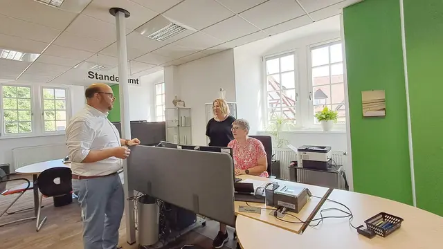 Das Bild zeigt Bürgermeister Meikel Dörr im Gespräch mit Büroleiterin Ursula Baumann-Schell und Kollegin Petra Walter im Bürgerbüro der Stadt Walldürn