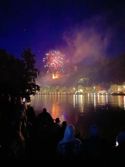 
Ein Abend, der sich in Licht verwandelt.

Wenn die Dämmerung über Miltenberg fällt, verwandelt sich die Stadt in eine Bühne. Die Altstadt wird zum Zuschauerraum, der Main zum Spiegel, die Burg zum Ausgangspunkt eines himmlischen Spiels. Das Feuerwerk der Michaelismesse ist mehr als ein Finale. Es ist ein Moment, in dem Miltenberg seine Geschichte, seine Menschen und seine Lage zwischen Fluss und Felsen feiert.