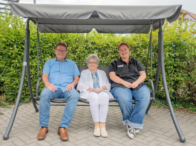 In dieser neu angeschafften Hollywoodschaukel lässt es sich wunderbar entspannen, finden neben einer Heimbewohnerin auch Altenheimpate Manfred Schüssler (links) und Laura Tschöp, Leiterin der sozialen Betreuung (rechts).  | Foto: Winfried Zang