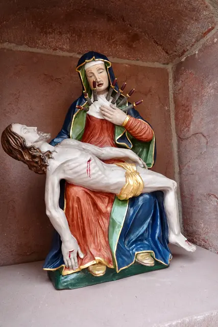 Der Schutz des Weges: Bildhäuschen an Schnittstellen des dörflichen Lebens fungierten als spirituelle Raststationen. Wer hier innehielt, suchte Trost bei der „Schmerzhaften Mutter“ und legte seine persönlichen Sorgen in ihre Hände. 