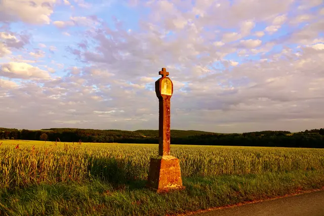 Der Marienbildstock im Madonnenländchen bei Eichenbühl‑Heppdiel steht flirrend in der Frühsommerhitze, als würde der Stein selbst zu glühen beginnen. Und die Madonna glänzt im weißen Licht des Tages, still und doch so lebendig, als hätte die Sonne ihr einen Atem eingehaucht.